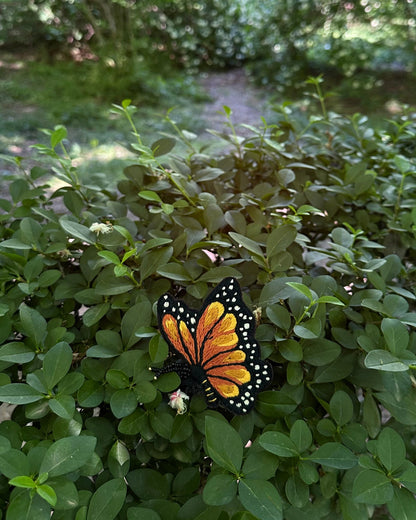 Butterfly brooch on a green leafy plant with a blurred natural background